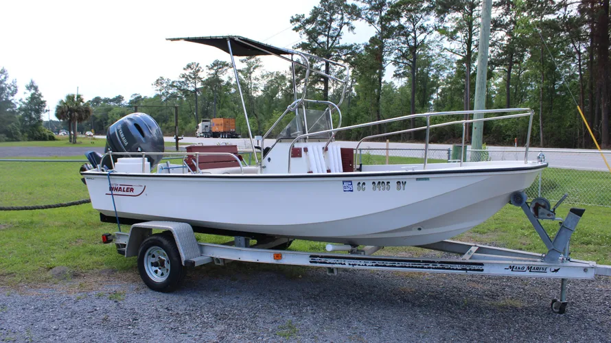 1982 Boston Whaler 17 Montauk center console boat on trailer, featuring Yamaha 90hp outboard engine, parked outdoors with trees in background.