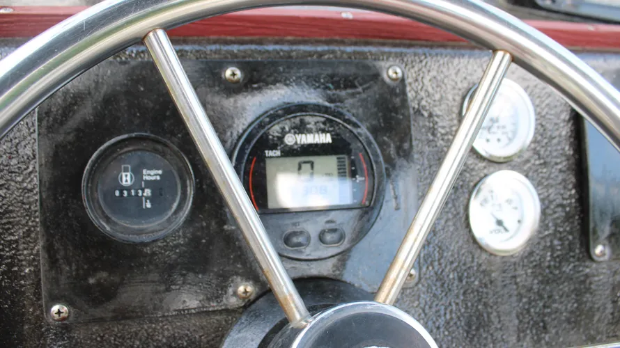 Steering wheel and Yamaha engine control panel of a 1982 Boston Whaler 17 Montauk, displaying engine hours and tachometer readings, emphasizing its low usage and functionality.