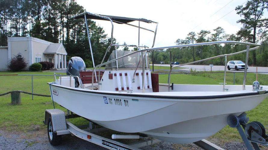 1982 Boston Whaler 17 Montauk center console boat with Yamaha 90hp outboard, featuring live well, on trailer in grassy area.