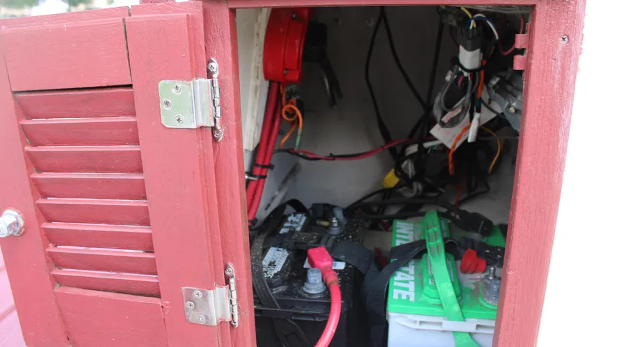 Interior view of a battery compartment in a boat, showcasing two marine batteries, wiring, and a red circuit breaker, relevant to the maintenance and functionality of the 1982 Boston Whaler 17 Montauk.
