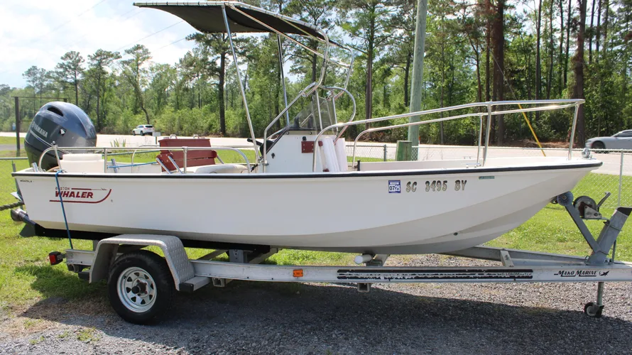 1982 Boston Whaler 17 Montauk center console boat on a trailer, featuring a Yamaha F90 outboard motor, set against a wooded background, highlighting its classic design and ready-to-go condition.