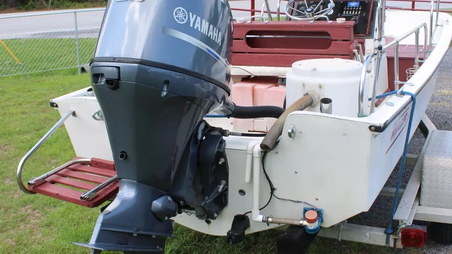Yamaha F90 outboard motor on a 1982 Boston Whaler 17 Montauk, showcasing engine details and boat features, with trailer in background.