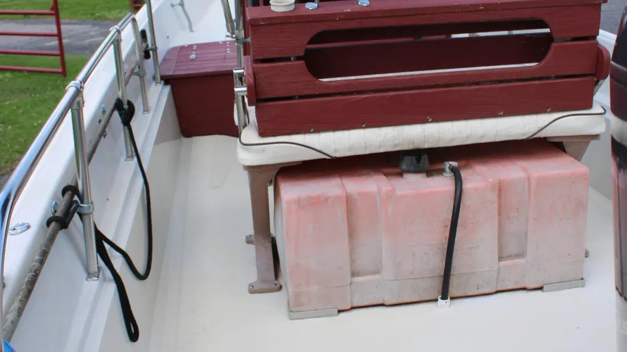 Interior view of a 1982 Boston Whaler 17 Montauk showing seating area, fuel tank, and storage compartments, highlighting its center console design and classic marine features.