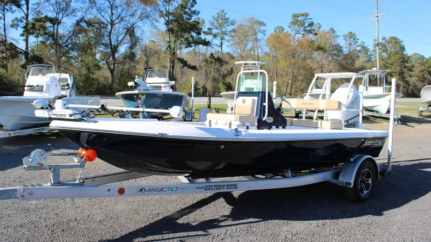 2025 Action Craft 17 Flyfisher boat on trailer, featuring a sleek design with a black hull and white accents, surrounded by other boats at Cape Romain Marine dealership.