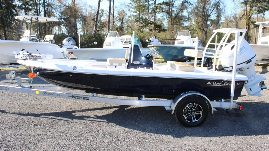 2025 Action Craft 17 Flyfisher boat on a trailer, featuring a Suzuki outboard engine, showcased in a marine dealership setting with other boats in the background.