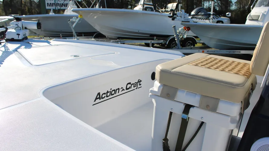 Action Craft logo on the deck of a 2025 Action Craft 17 Flyfisher boat, featuring a beige cushioned seat and a clean, white surface, with additional boats visible in the background.
