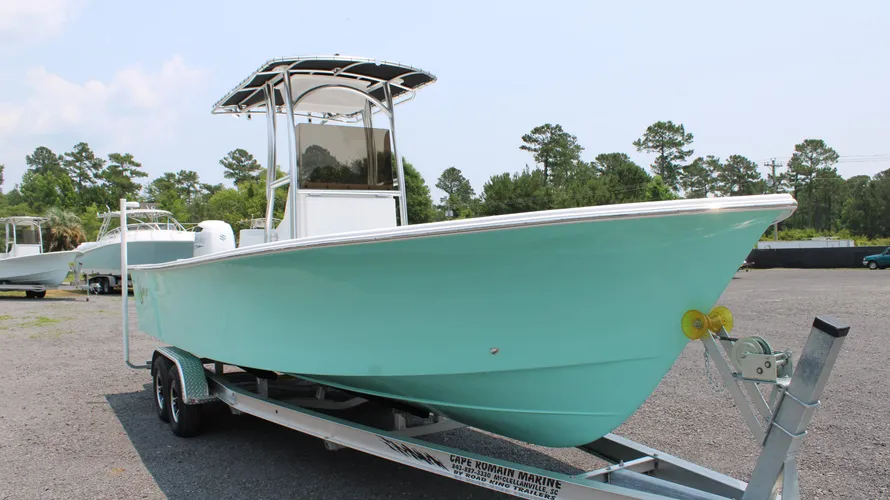2025 C-Hawk 25 Center Console boat in mint green, showcasing its sleek design and trailer, set in a marine dealership lot, emphasizing saltwater fishing capabilities and built for durability.