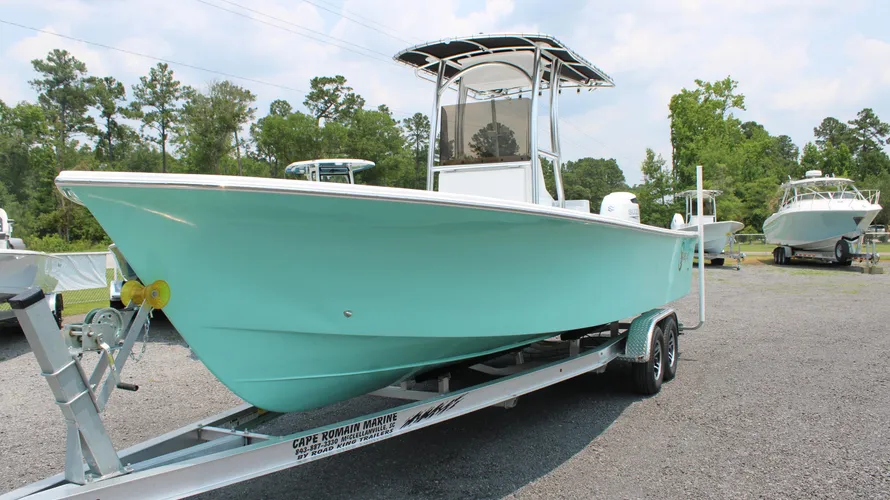 2025 C-Hawk 25 Center Console boat in turquoise color on a trailer, showcasing its sleek design and saltwater fishing capabilities, with additional boats in the background at Cape Romain Marine dealership.