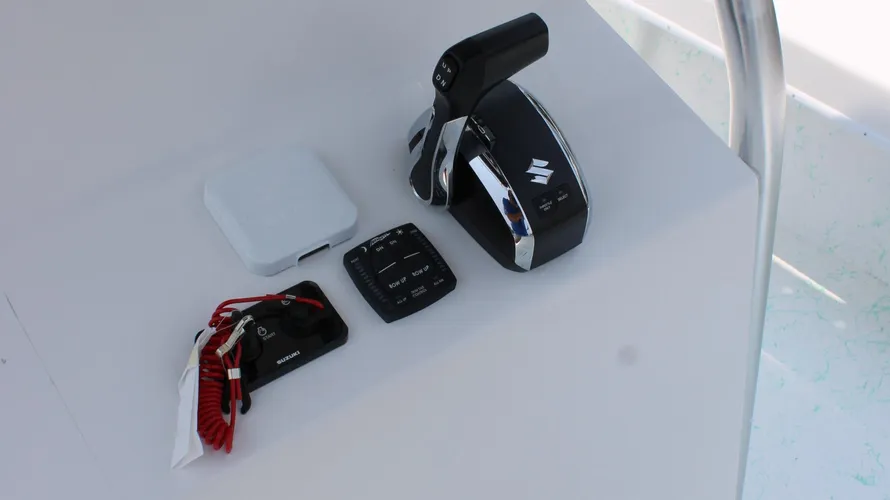 Suzuki boat control panel and remote accessories on a white surface, showcasing features relevant to the 2025 C-Hawk 25 Center Console.