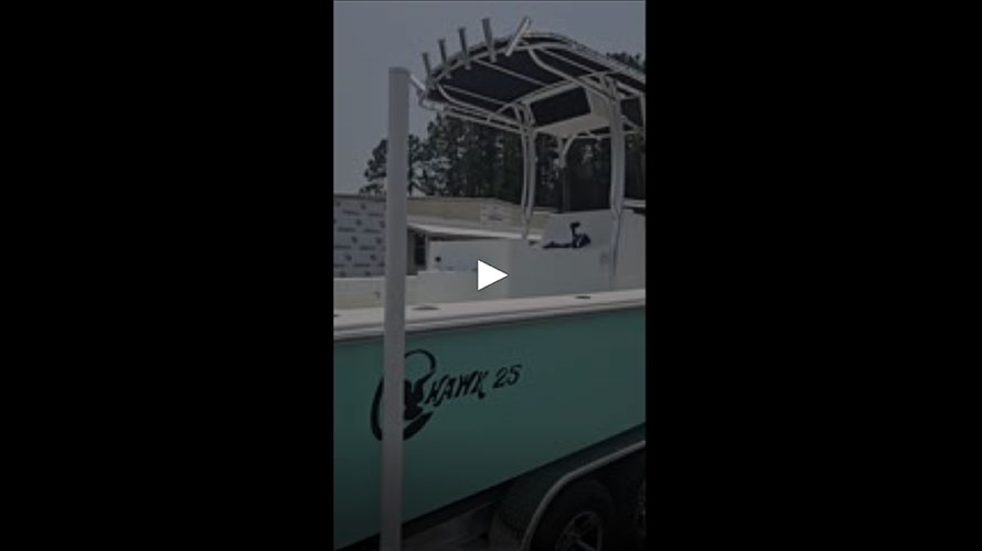 2025 C-Hawk 25 Center Console boat with a light blue hull, featuring a T-top and rod holders, showcased in a dealership setting, emphasizing its saltwater fishing capabilities and robust design.