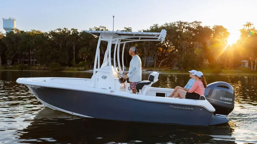 2025 Tidewater Boats 198CC in action on water, featuring a Yamaha outboard engine, with a captain steering and two passengers enjoying the ride during sunset.