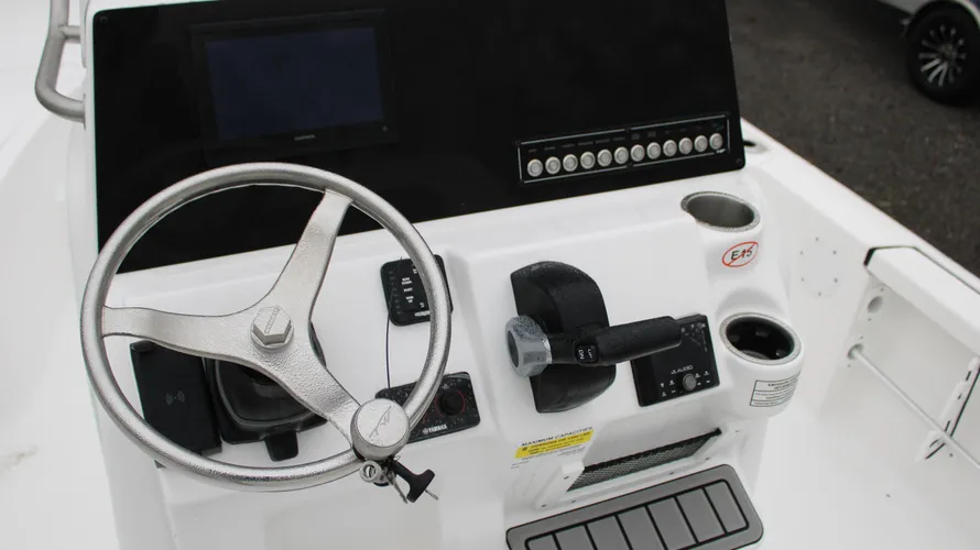 Boat dashboard featuring steering wheel, throttle control, and electronic display, showcasing the interior of the 2025 Tidewater Boats 2110 Bay Max, designed for marine navigation and control.
