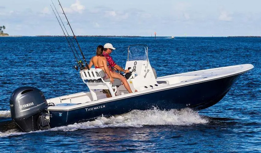 2025 Tidewater Boats 2110 Bay Max in blue mist color, with two people onboard, cruising on water, featuring Yamaha outboard engine, fishing rods visible, showcasing recreational boating experience.