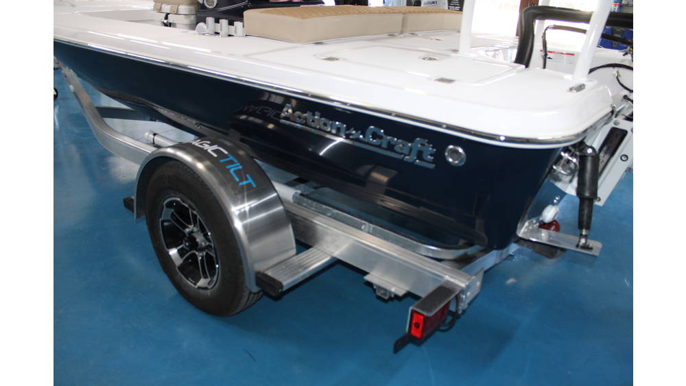 2025 Action Craft 17 Flyfisher boat on a bunk trailer, featuring a sleek blue hull and Suzuki outboard motor, showcased in a marine dealership setting.