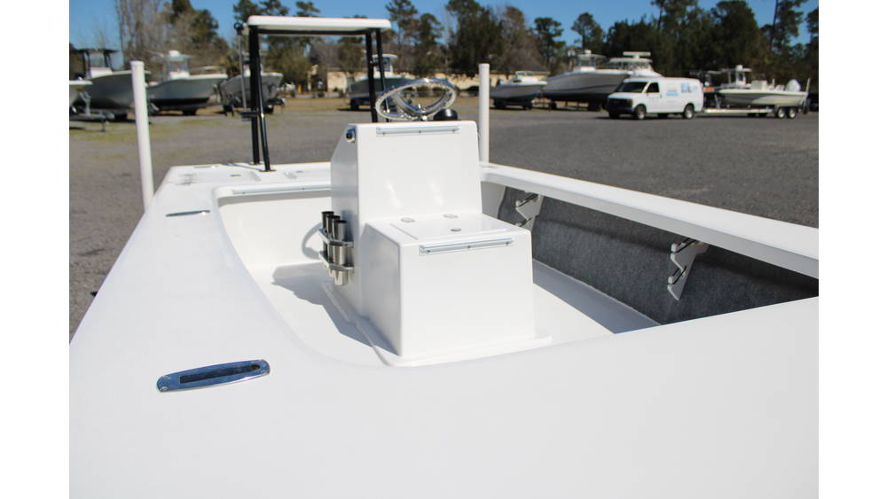 Interior view of the 2025 17 Tournament Mitzi Skiff featuring a white layout, center console with steering wheel, and storage compartments, set against a backdrop of other boats at Cape Romain Marine dealership.