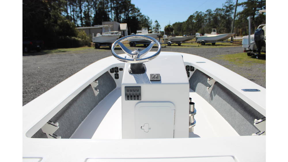 Interior view of a 2025 17 Tournament Mitzi Skiff featuring a steering wheel, control panel, and spacious layout, showcasing the boat's design and functionality, with other boats visible in the background at Cape Romain Marine.