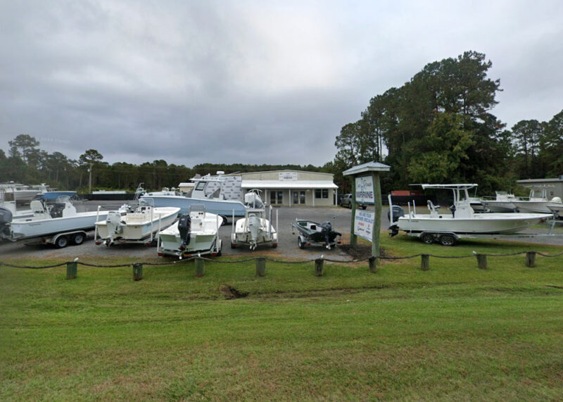 Cape Romain Marine dealership in McClellanville, SC, featuring a variety of new and pre-owned boats, with the dealership building visible and surrounded by several boats on display.